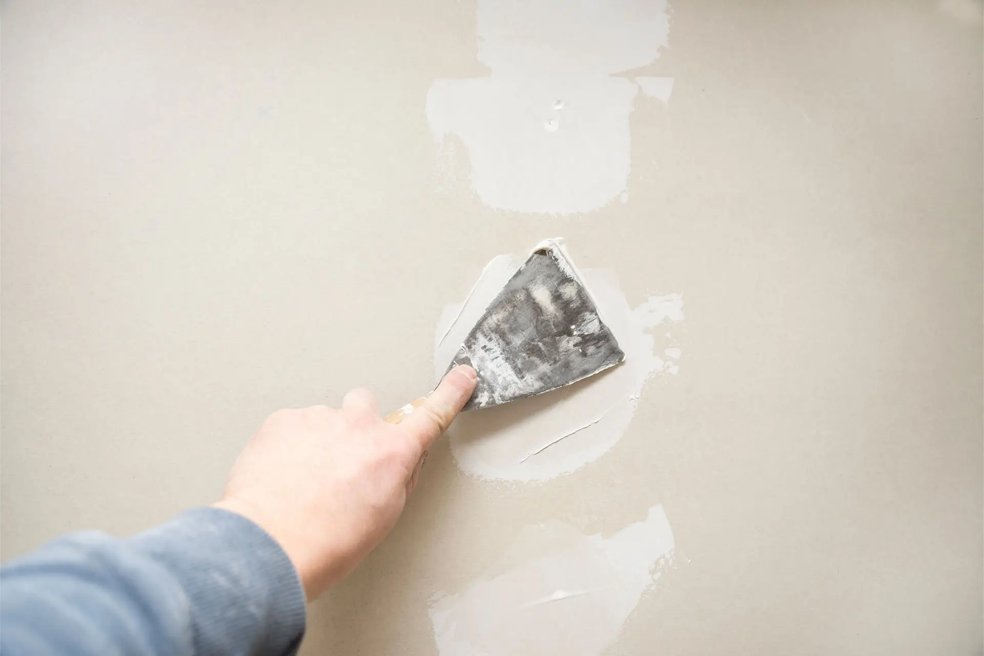 A person painting a wall with a brush, focused on applying a fresh coat of paint.
